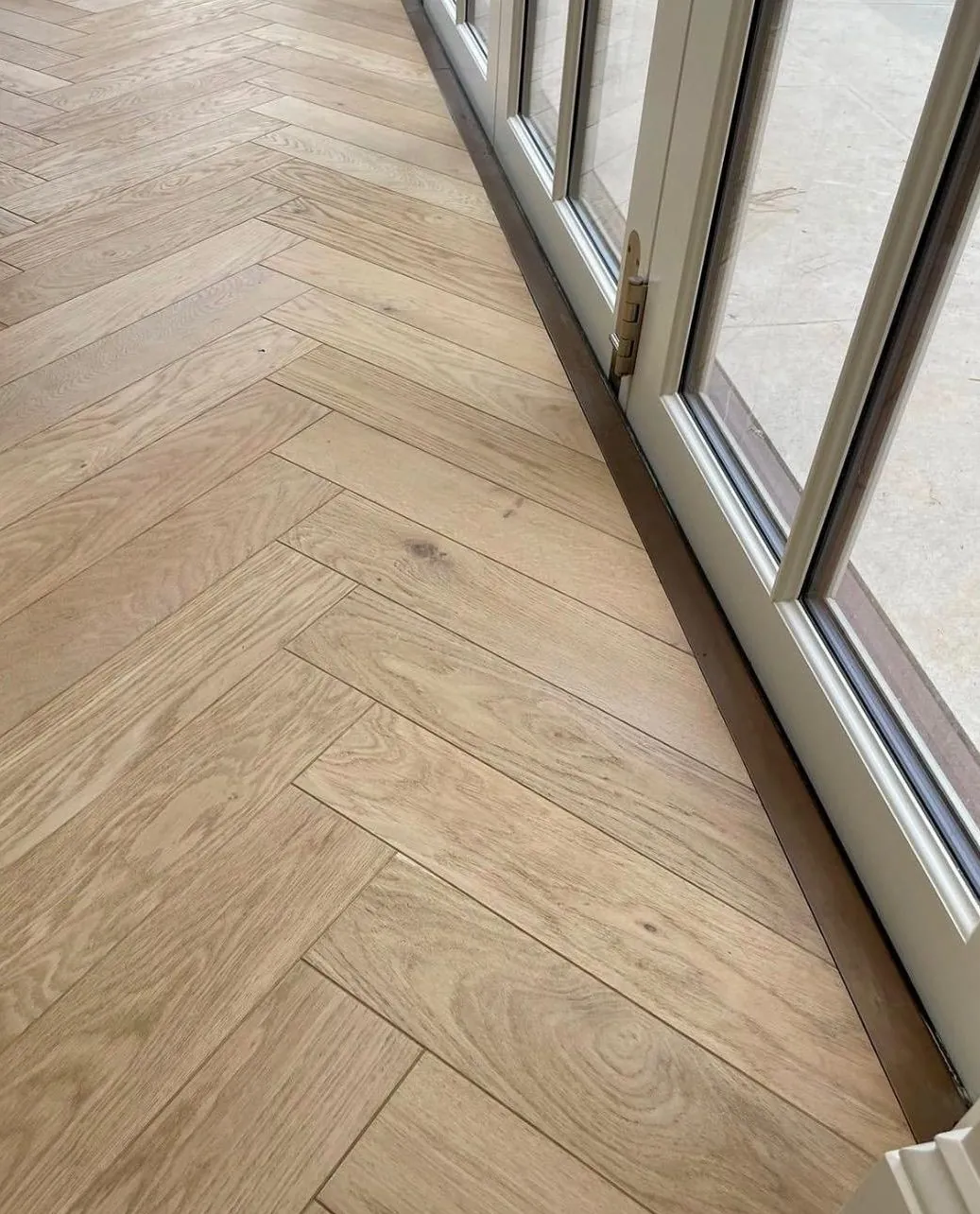 Herringbone oak floor finished neatly along bifold doors | Northfold Flooring