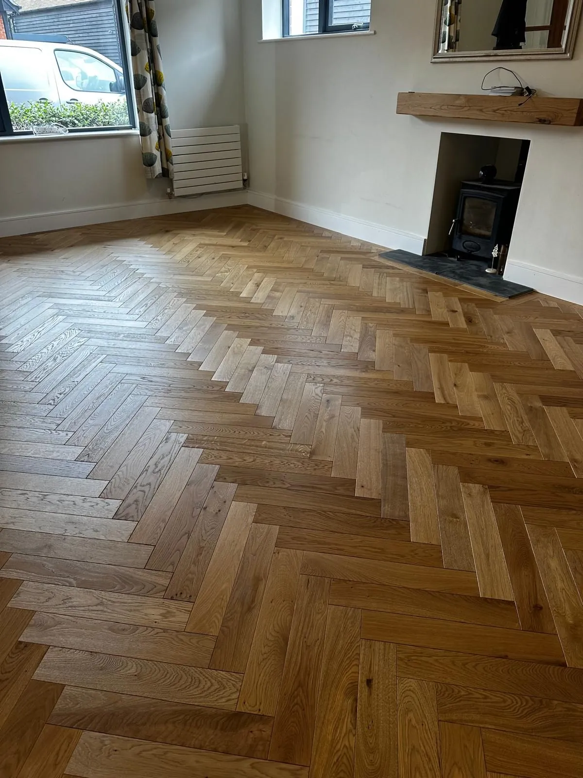 Natural herringbone oak flooring by a fireplace | Northfold Flooring