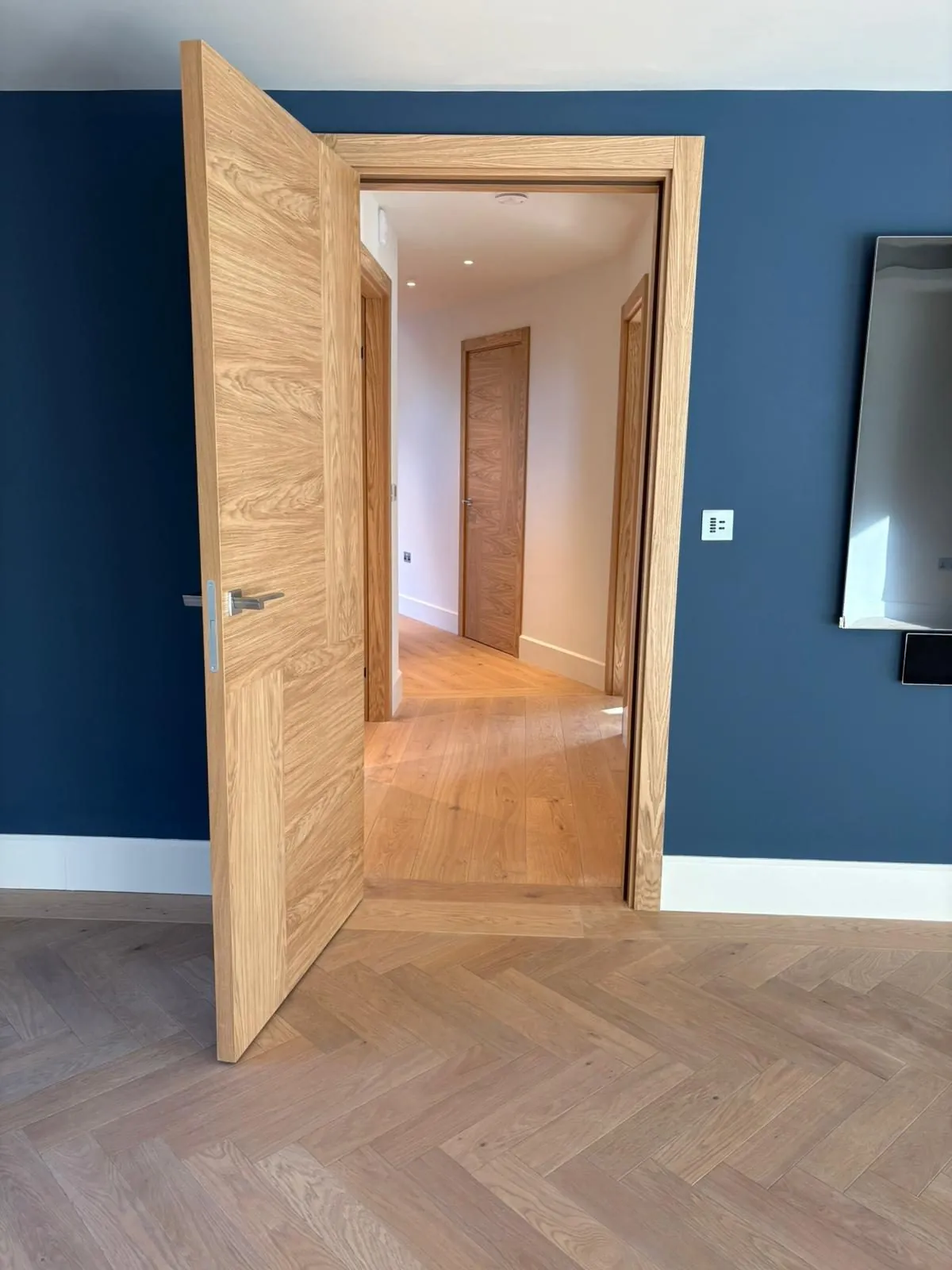 Herringbone oak floor running through an oak door into the next room | Northfold Flooring