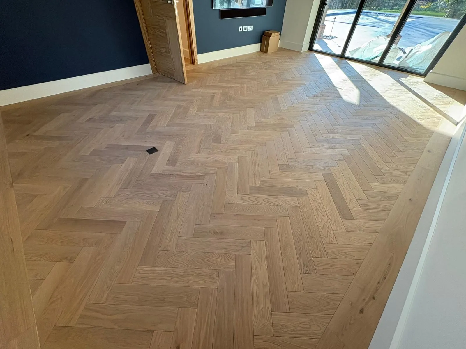 Herringbone oak flooring fitted in a media room with garden doors | Northfold Flooring