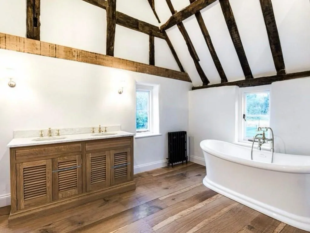 Wide plank oak flooring in a barn conversion bathroom with a freestanding bath | Northfold Flooring