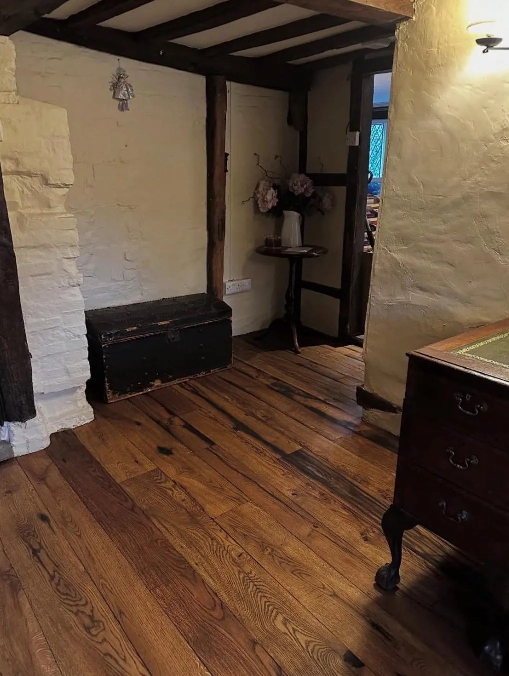 Rustic oak plank flooring installed in a beamed cottage